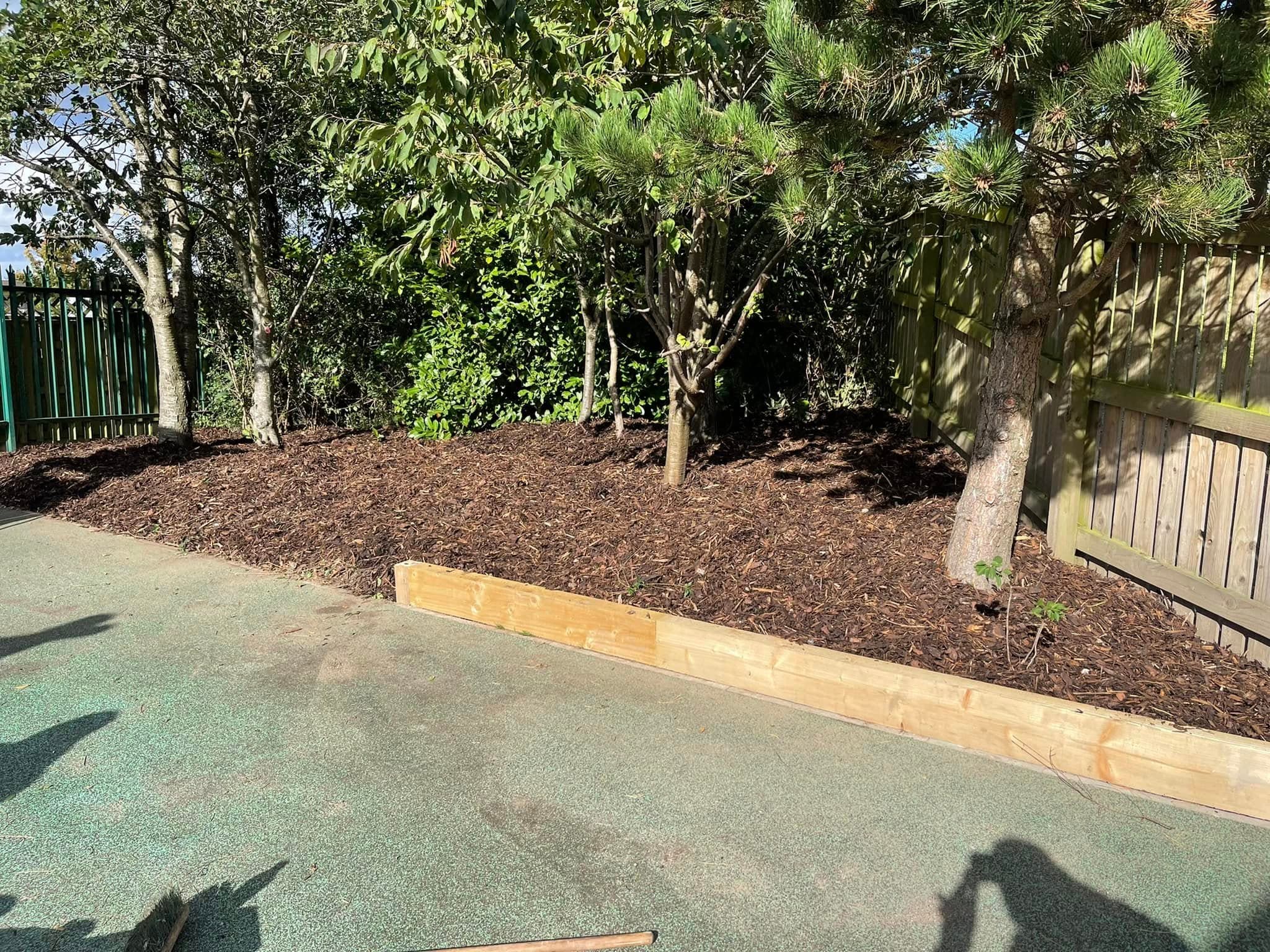 New planting bed with timber edging cut into a grass bank