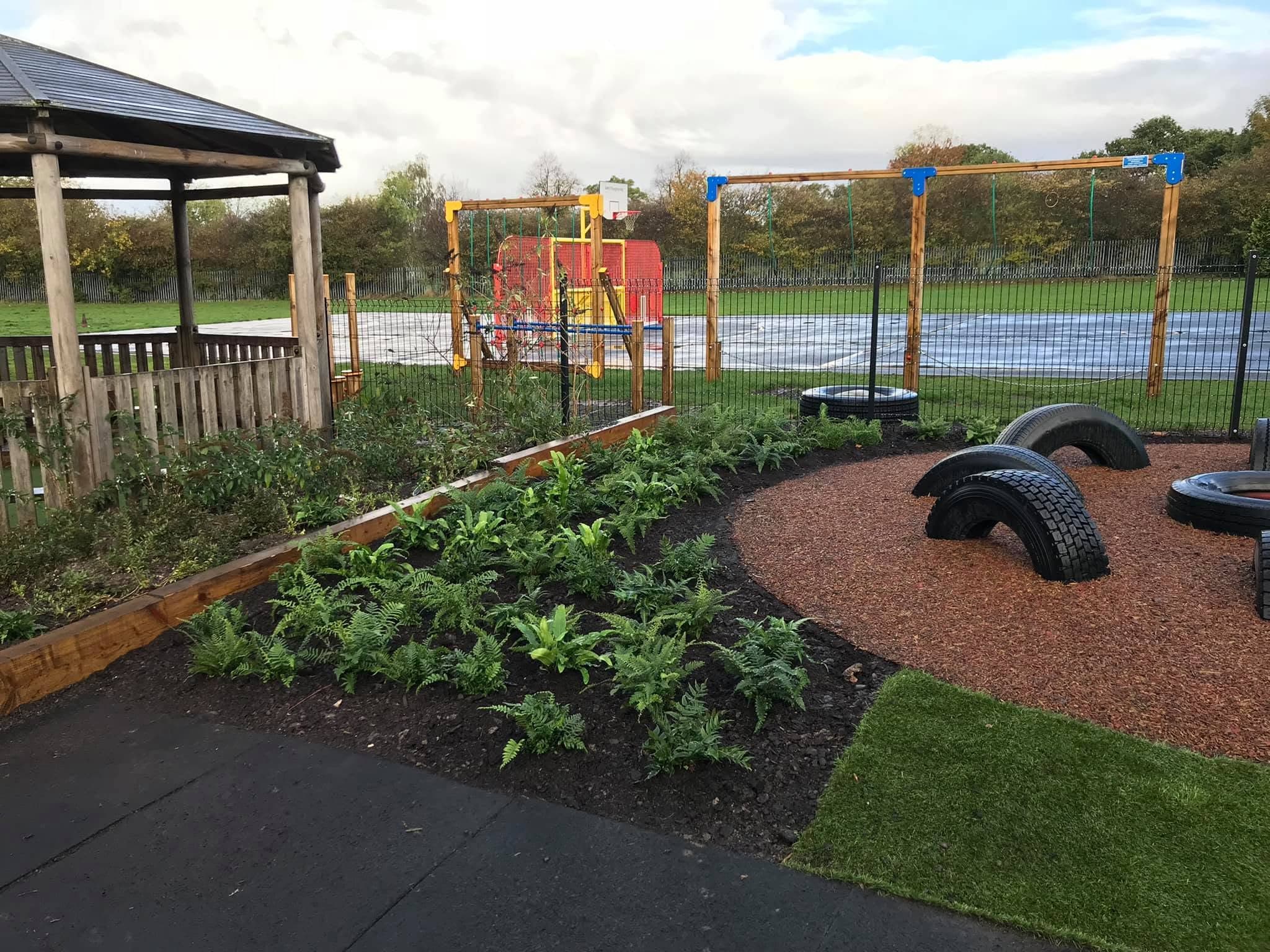School play area with planted beds, play equipment and bark surfacing